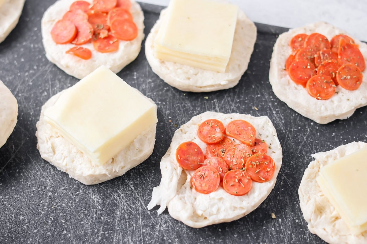 Filling pizza waffles with cheese and pepperoni.