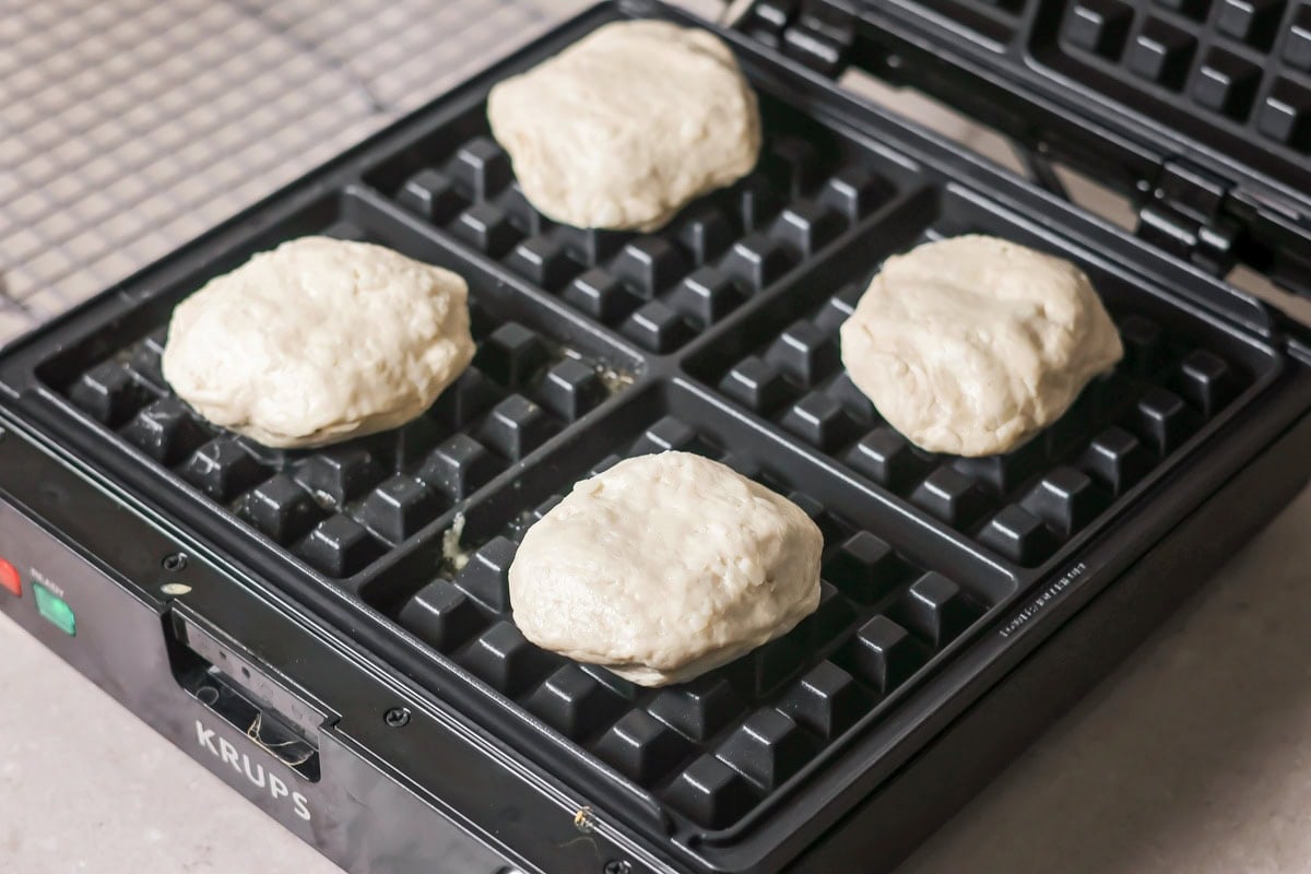 Pizza waffle dough on a waffle maker ready to bake.