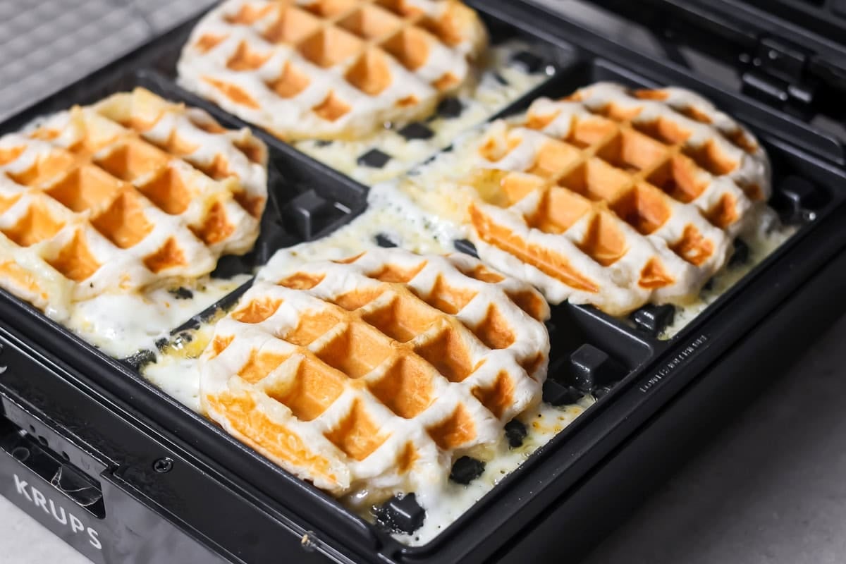 Pizza waffles cooking on a waffle maker.
