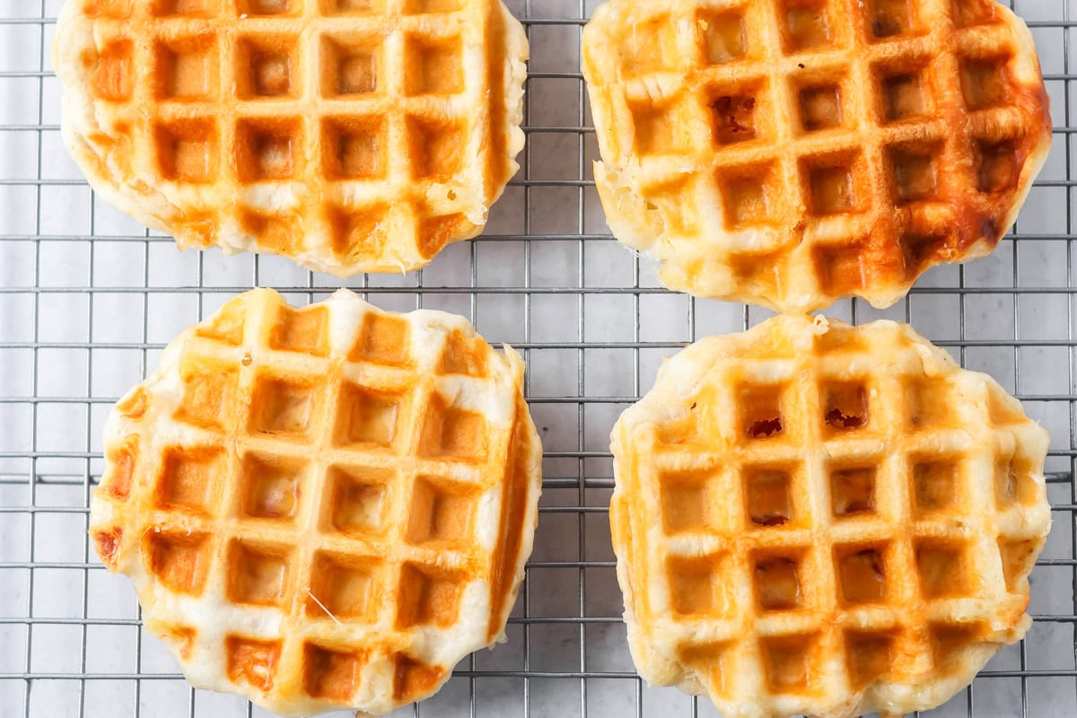 Cooked pizza waffles on a cooling rack.