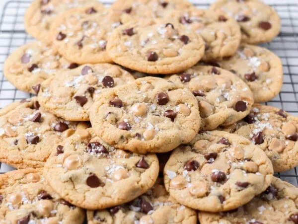 Salted caramel chocolate chip cookies stacked together on wire rack.
