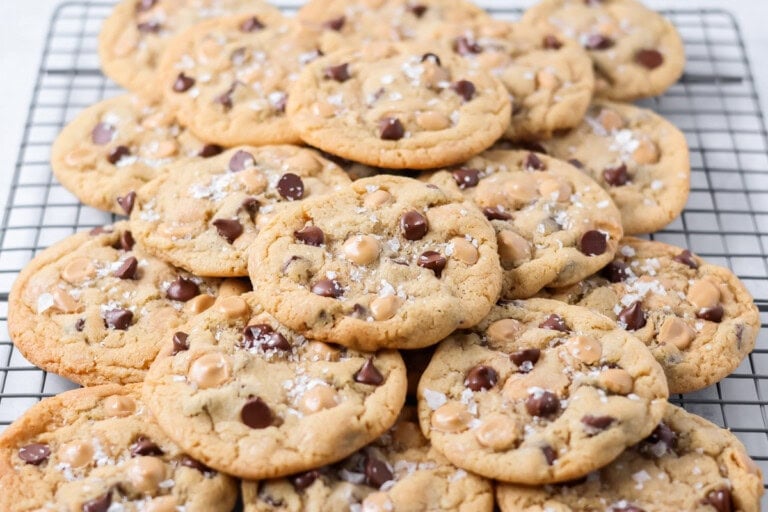 Salted caramel chocolate chip cookies stacked together on wire rack.