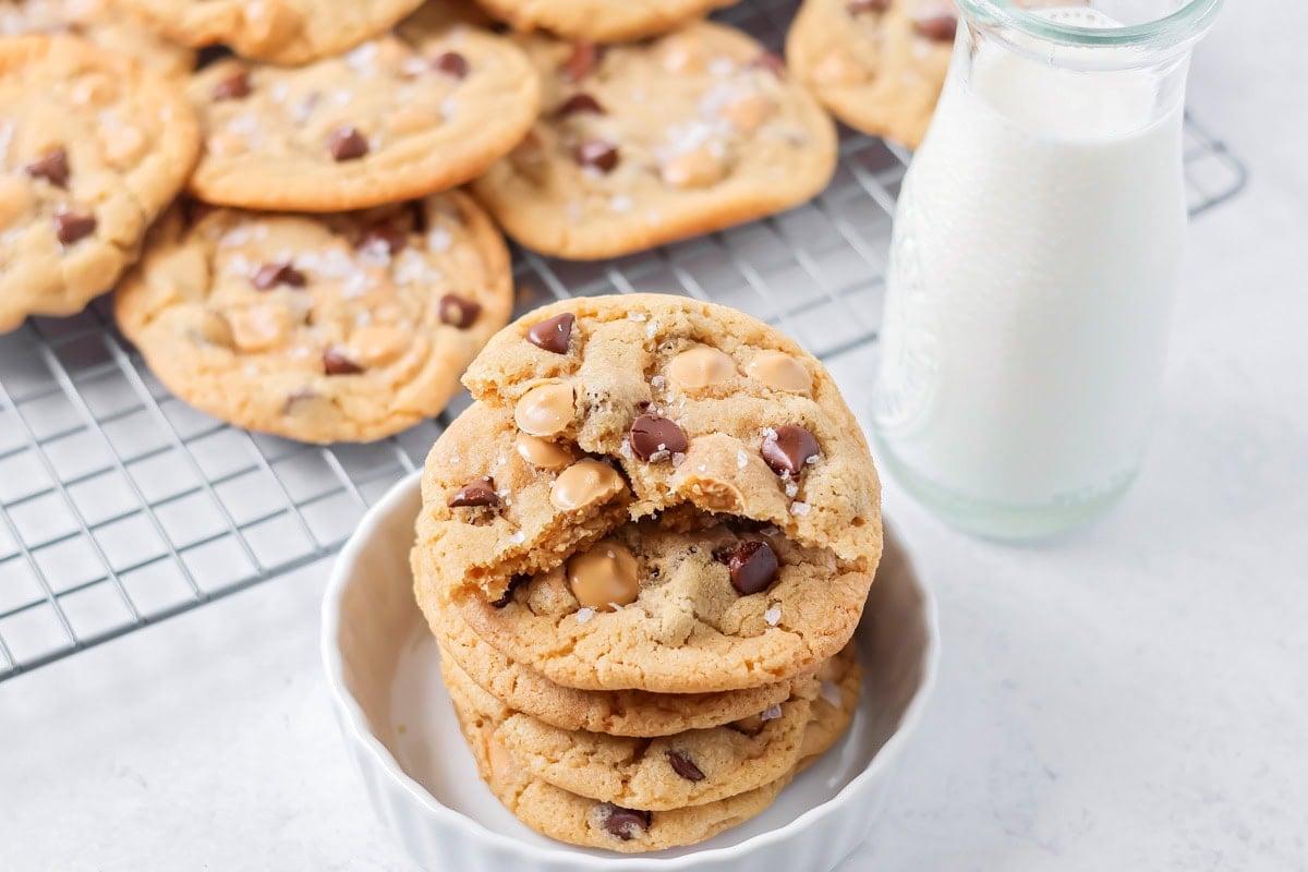 Salted Caramel chocolate chip cookies stacked on each other with cup of milk.