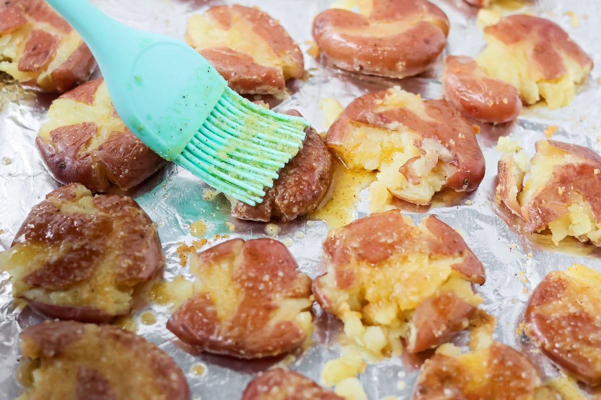 Brushing other side of smashed potatoes with oil and seasonings.