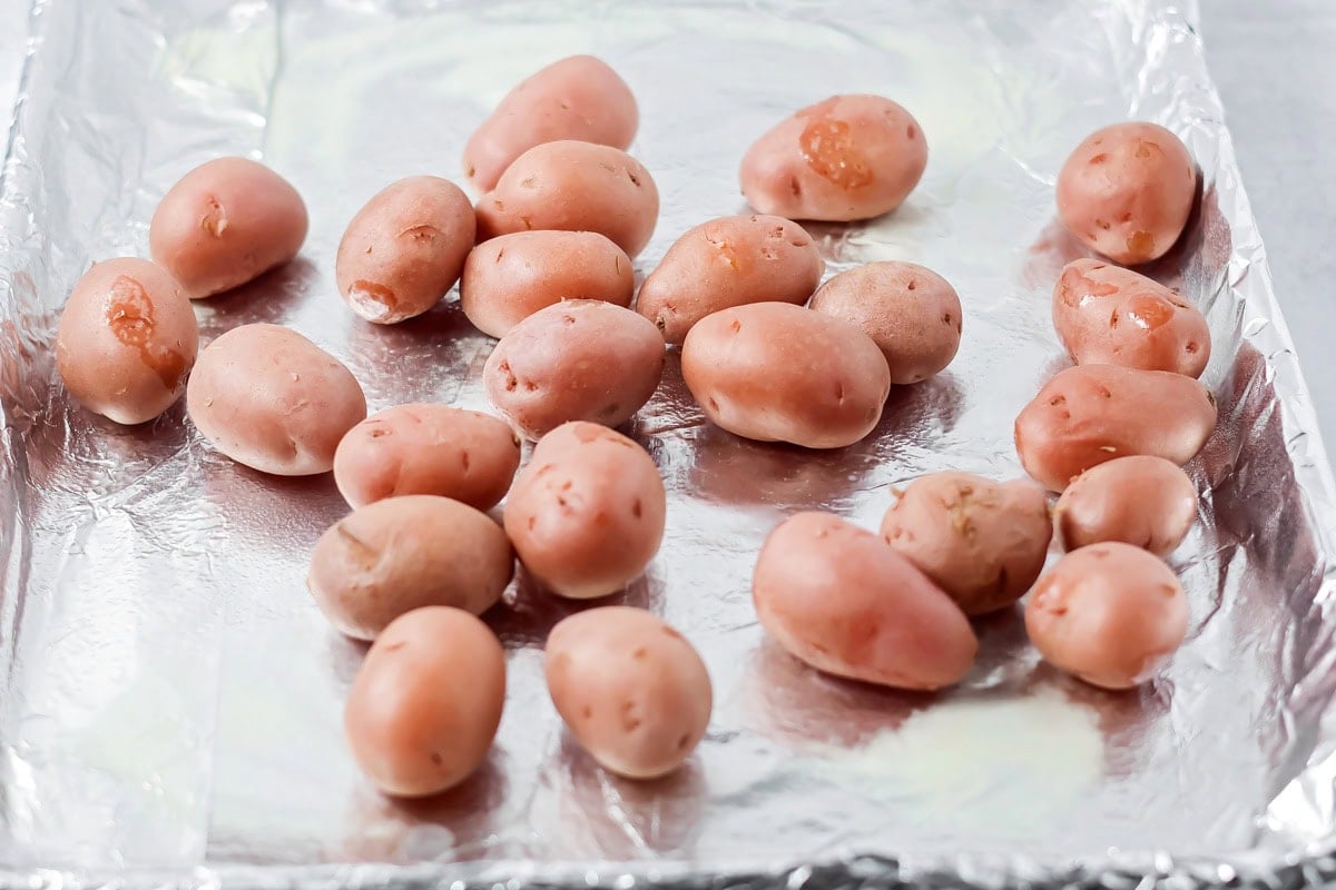 Boiled baby red potatoes on foil lined cookie sheet.