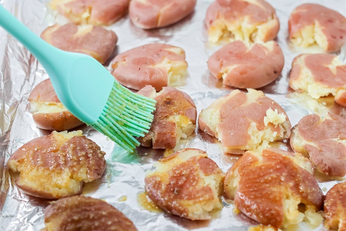 Brushing red potatoes with oil and seasonings.