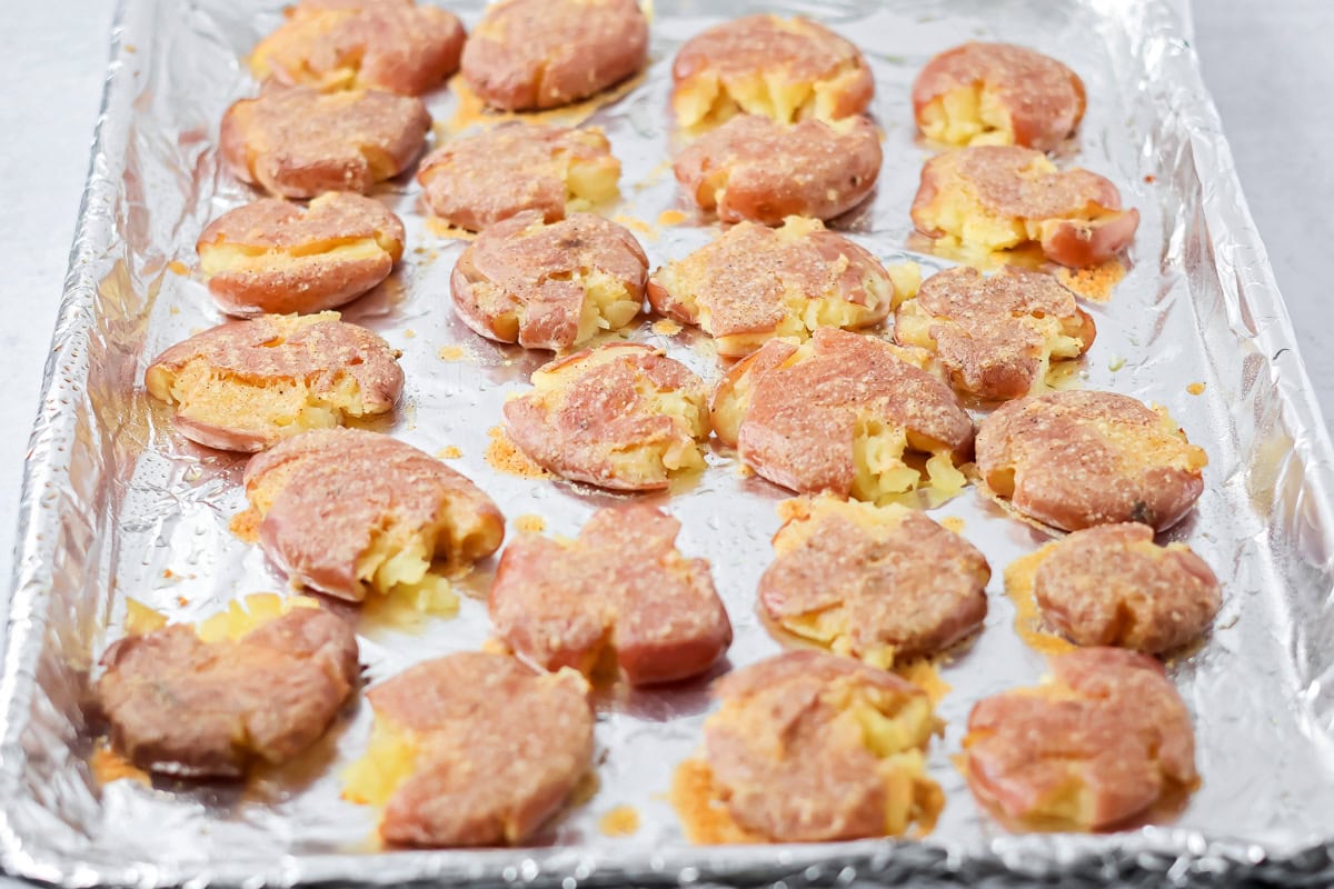 Smashed potatoes ready to bake on sheet pan.
