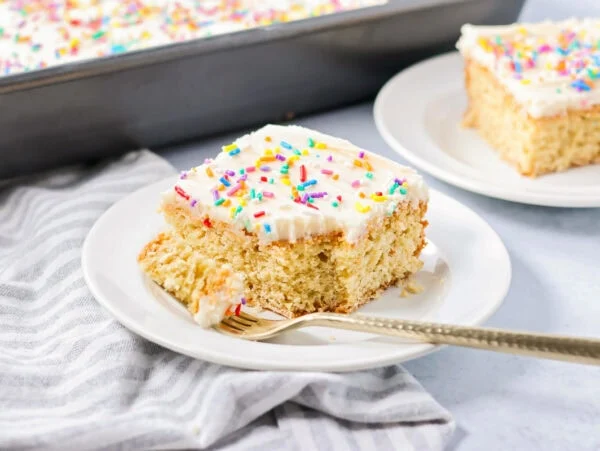 A slice of sugar cookie cake topped with frosting and sprinkles.