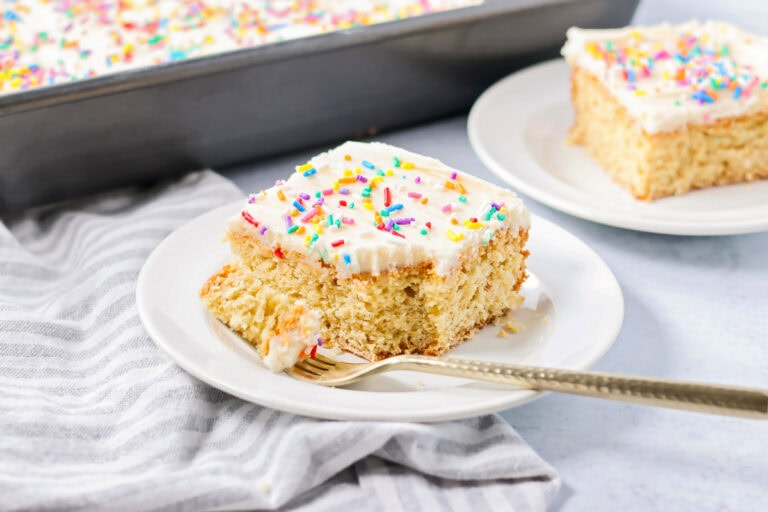 A slice of sugar cookie cake topped with frosting and sprinkles.
