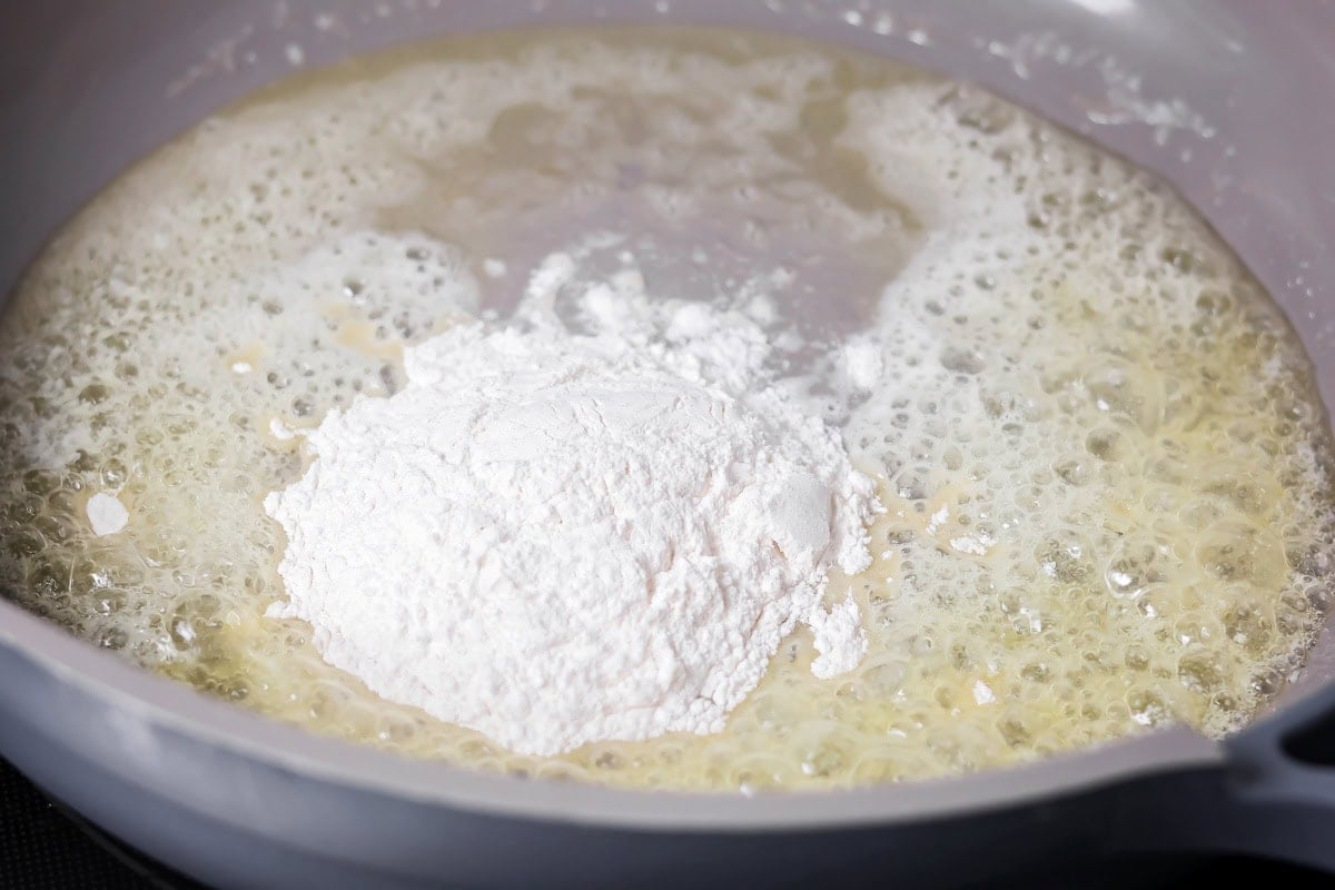 Adding flour to melted butter in a pan.