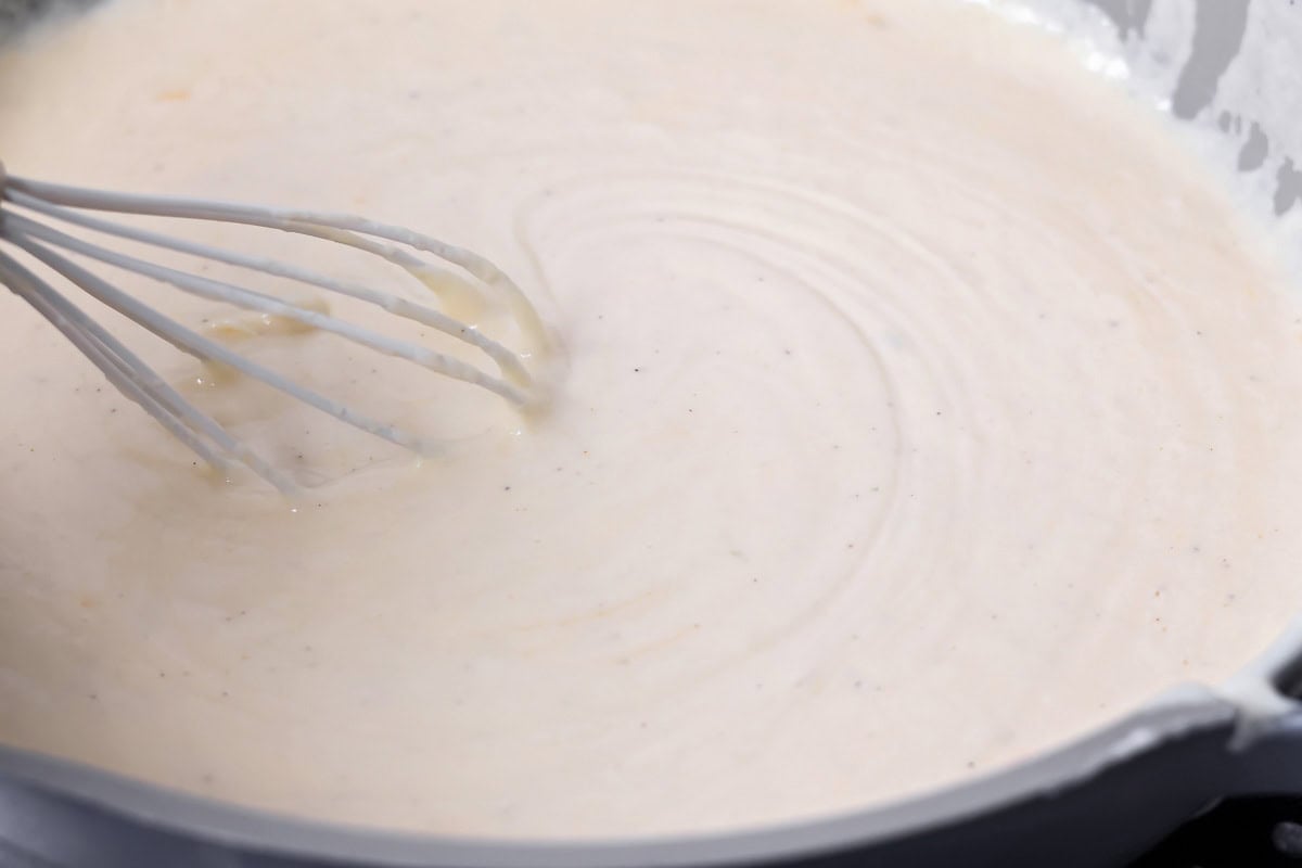 Whisking white sauce for baked mac and cheese.