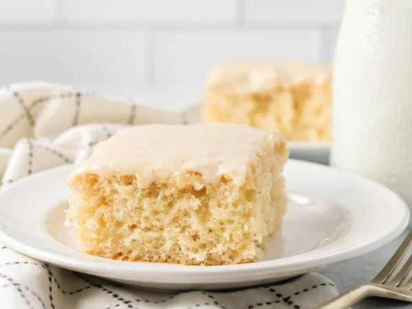 Buttermilk cake slice glazed and served on a white plate.