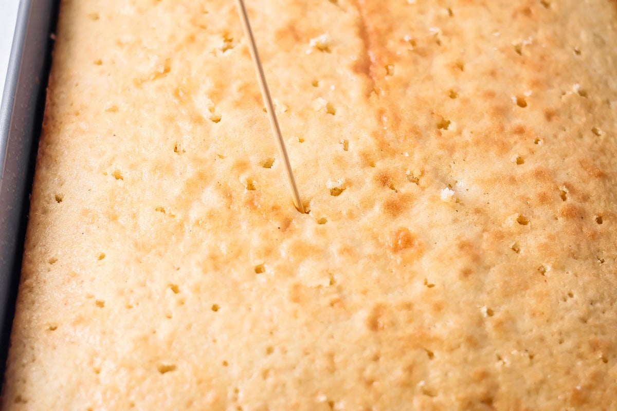 Poking holes in buttermilk cake preparing for glaze.
