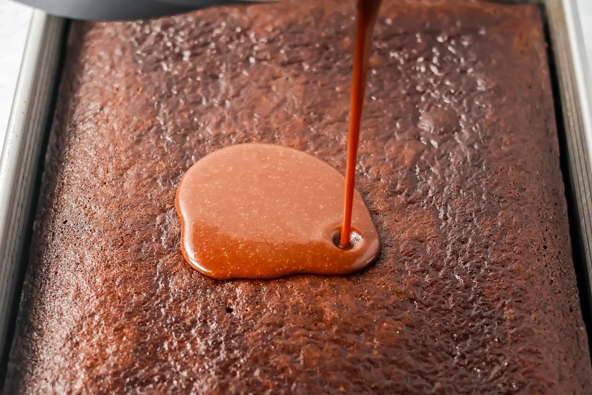 Pouring frosting on a chocolate pumpkin cake.