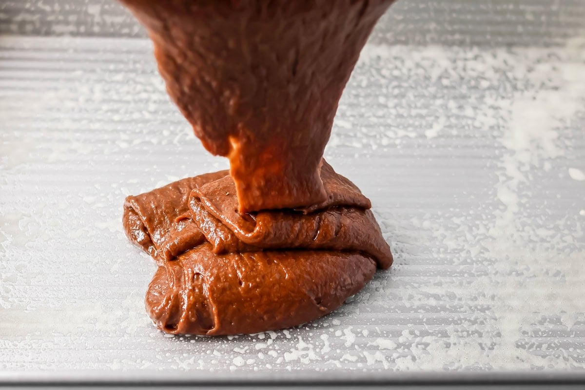 Pouring chocolate pumpkin cake batter in a baking dish.