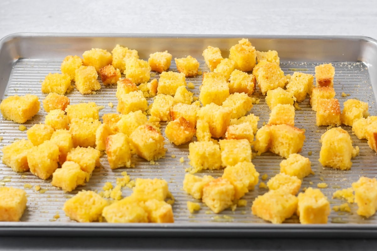 Cornbread croutons on a baking sheet ready to be browned.