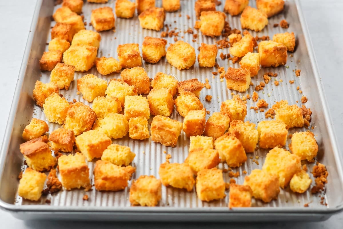 Cornbread croutons browned on a baking sheet.