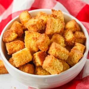 Baked cornbread croutons in a white bowl.