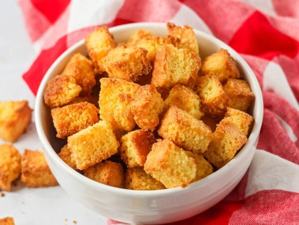 Baked cornbread croutons in a white bowl.
