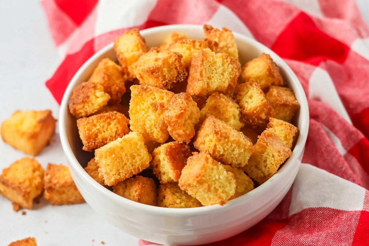 Baked cornbread croutons in a white bowl.