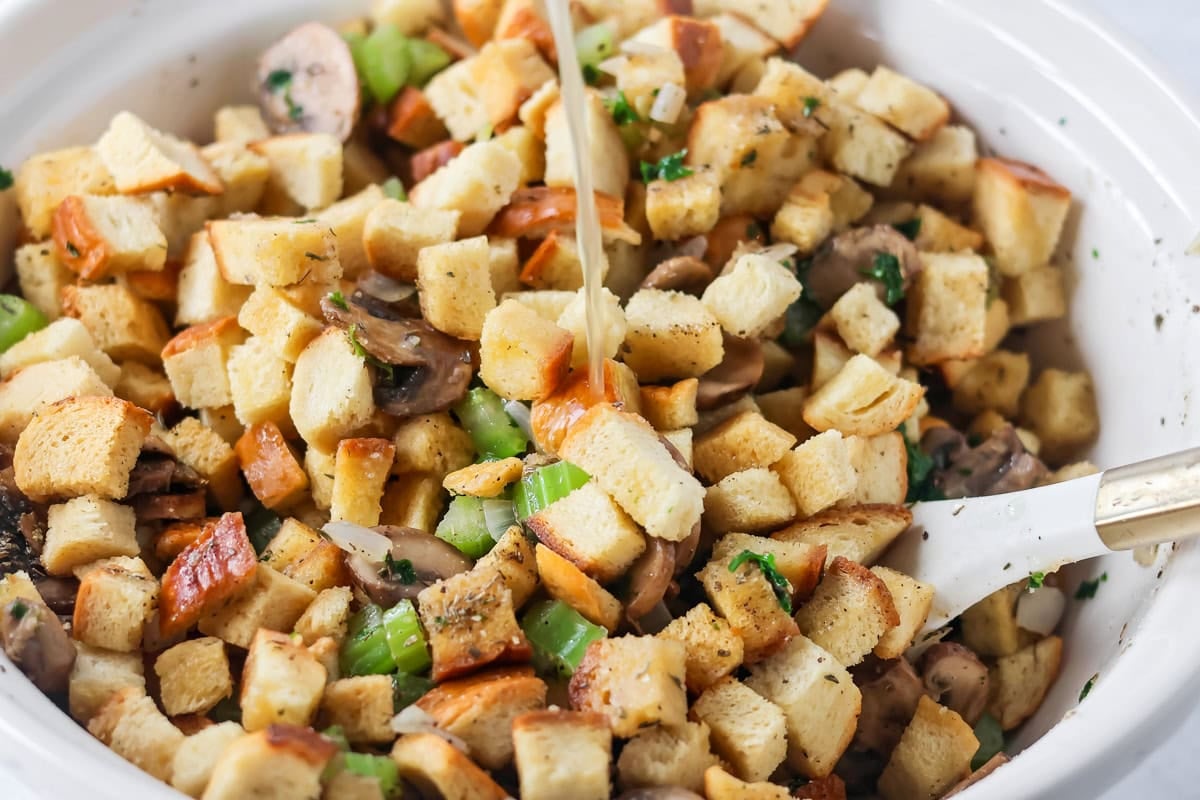Adding broth to crock pot stuffing.