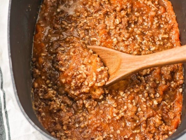 Scooping a serving of crock pot sweet potato casserole.