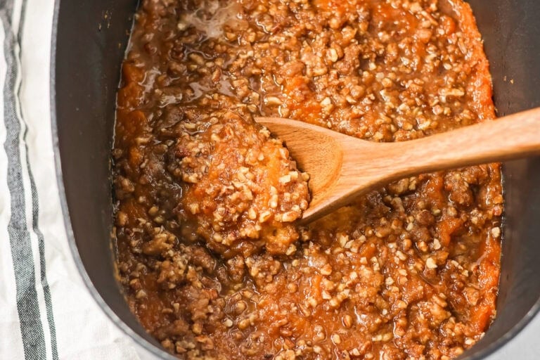 Scooping a serving of crock pot sweet potato casserole.