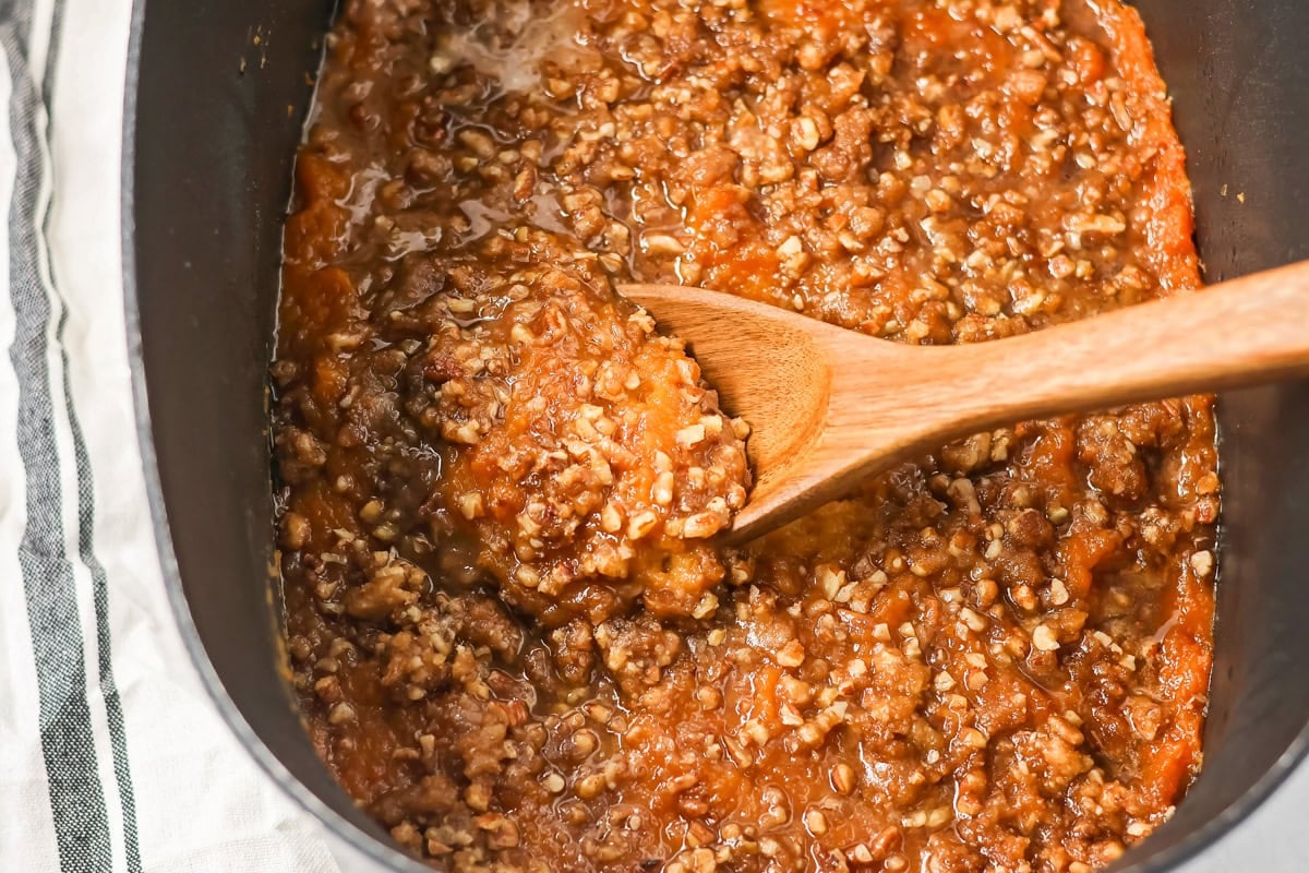 Scooping a serving of crock pot sweet potato casserole.