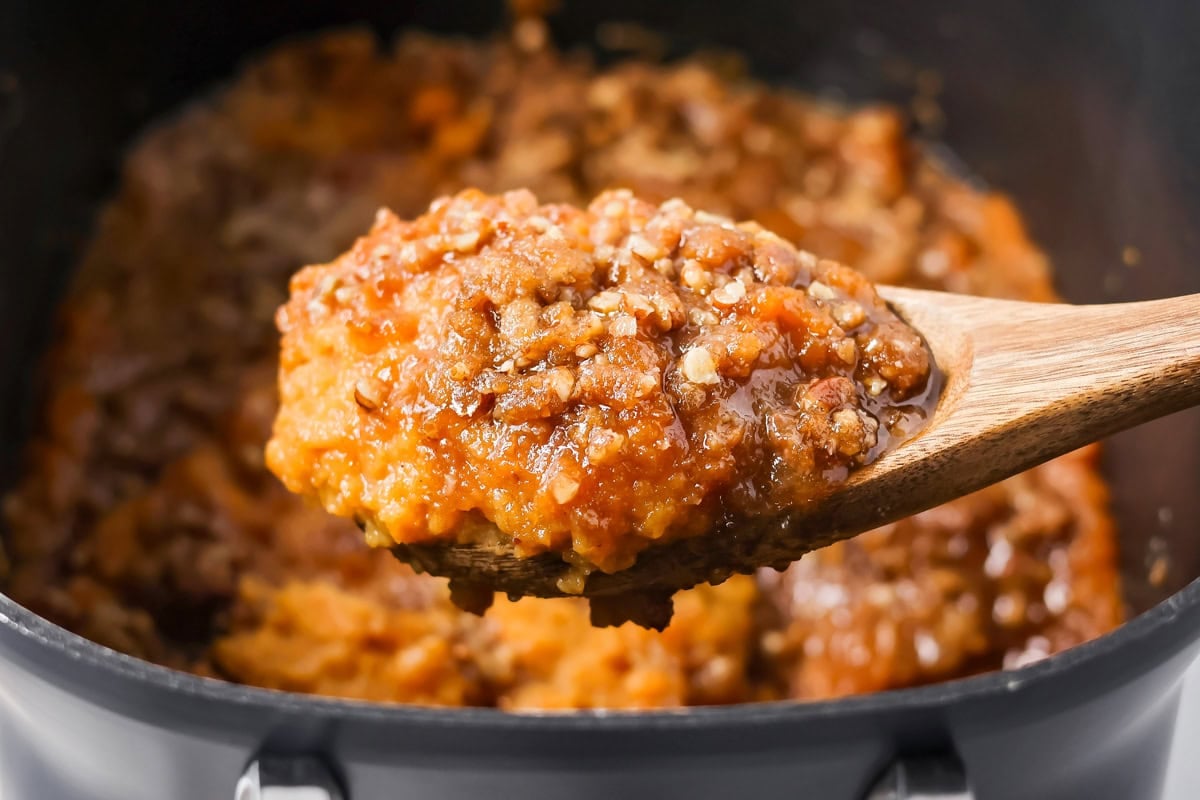 Crockpot sweet potato casserole being scooped out of slow cooker.