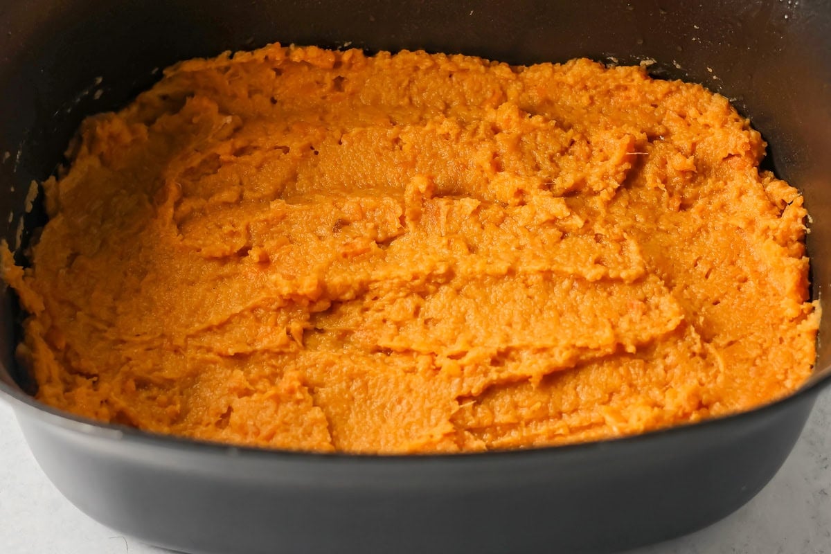 Spreading sweet potato casserole in a pot.