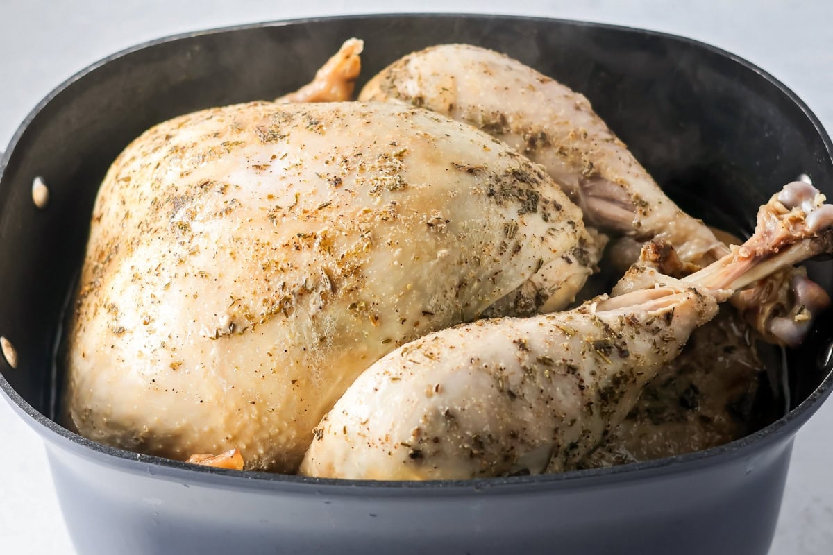 Seasoning crock pot turkey in a pan.