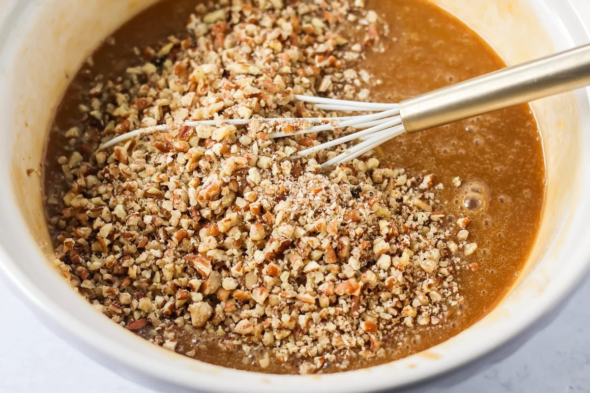 Adding chopped pecans to the custard pecan pie filling.
