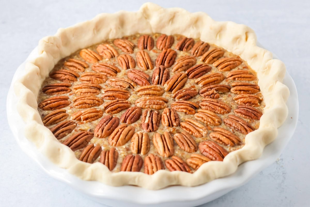 A custard pecan pie ready to be baked.