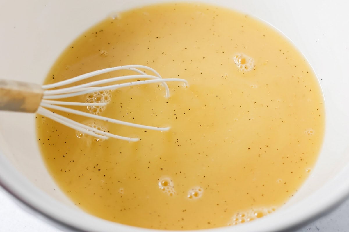 Whisking broth and seasonings in a bowl for make ahead stuffing.