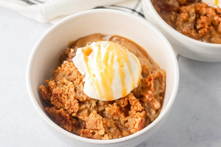 A serving of pecan pie dump cake topped with vanilla ice cream and caramel sauce.
