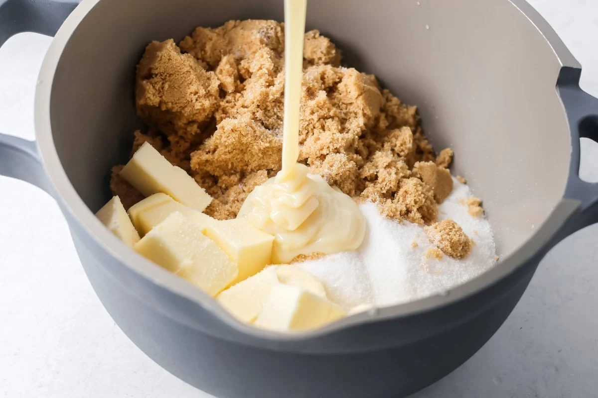 Sugar, butter, and sweetened condensed milk in a pot for making pecan pie dump cake.