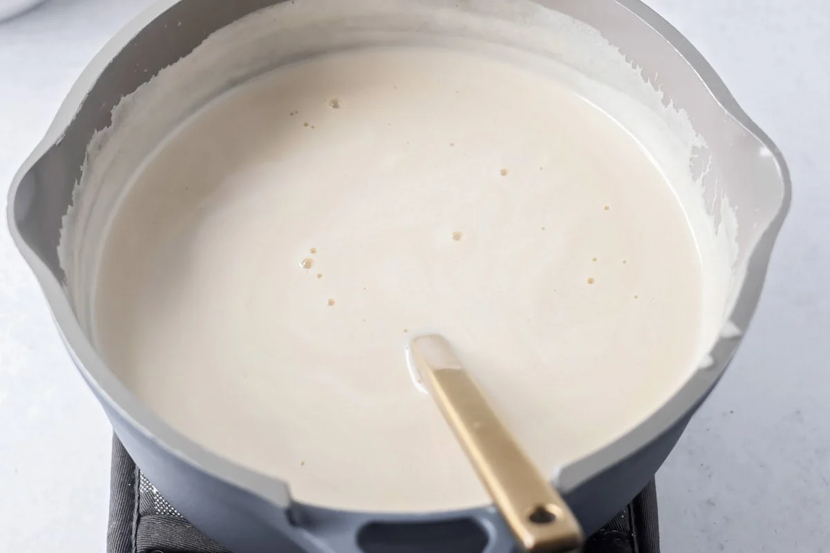 Stirring pecan pie dump cake filling in a pot.