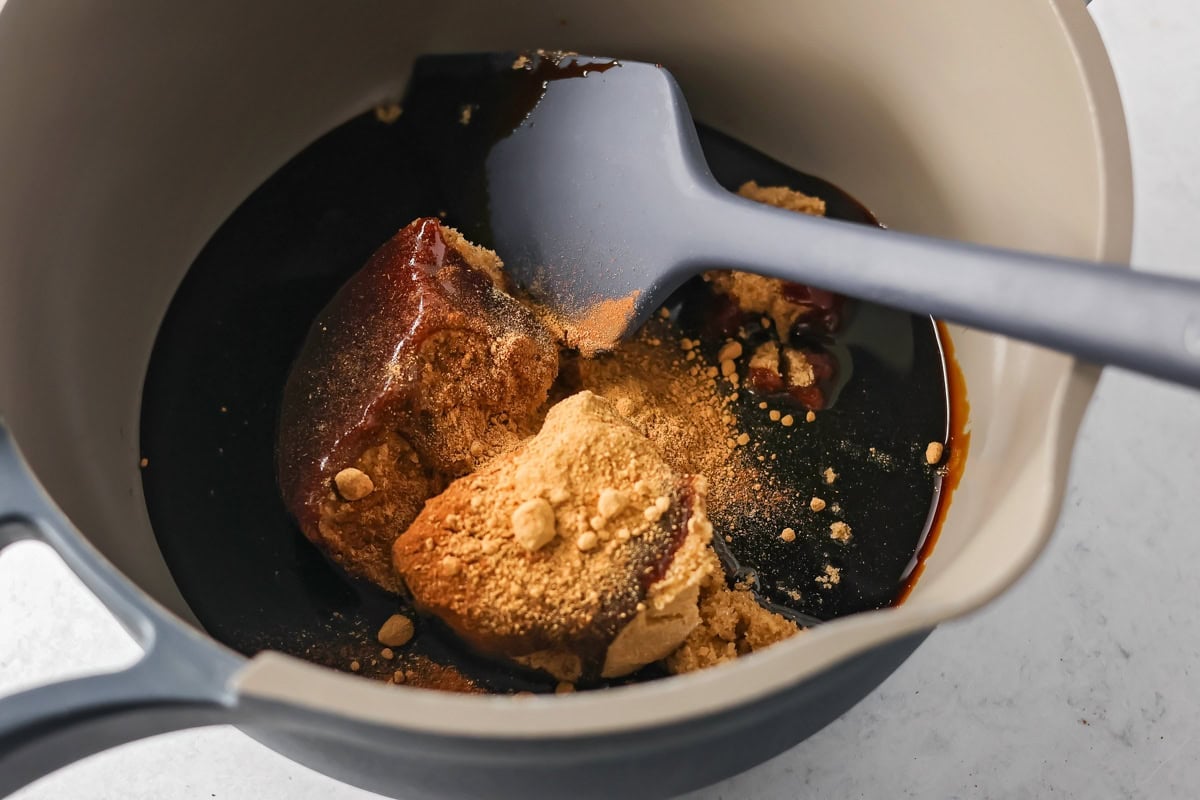 Adding brown sugar to molasses mixture for making pepparkaka dough.