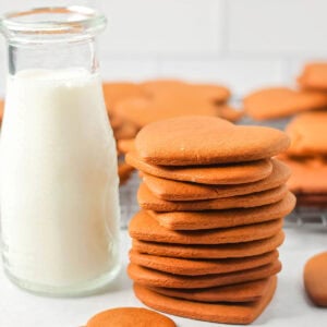 Pepparkaka cookies stacked on a counter with milk.