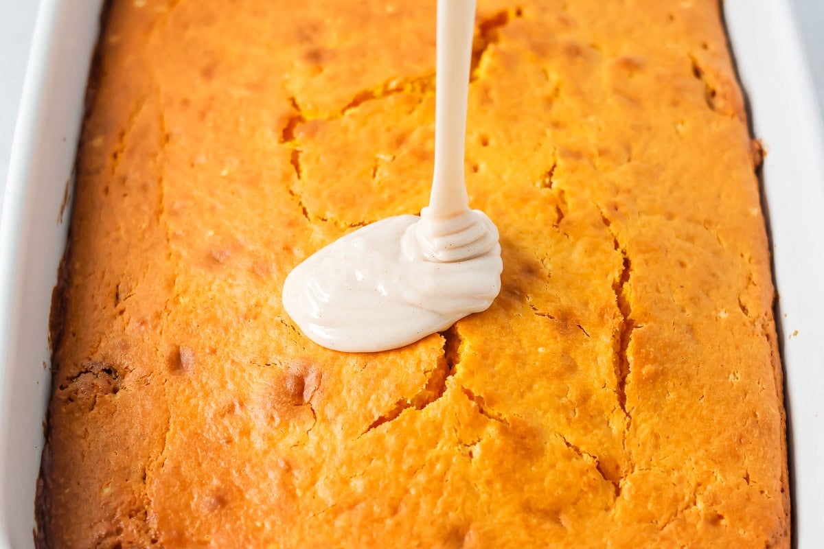 Pouring glaze on a baked pumpkin honey bun cake.