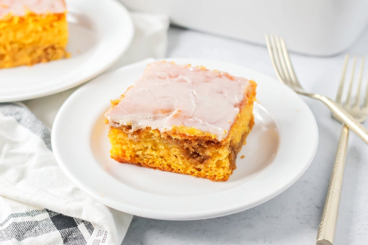 A slice of frost pumpkin honey bun cake on a white plate.