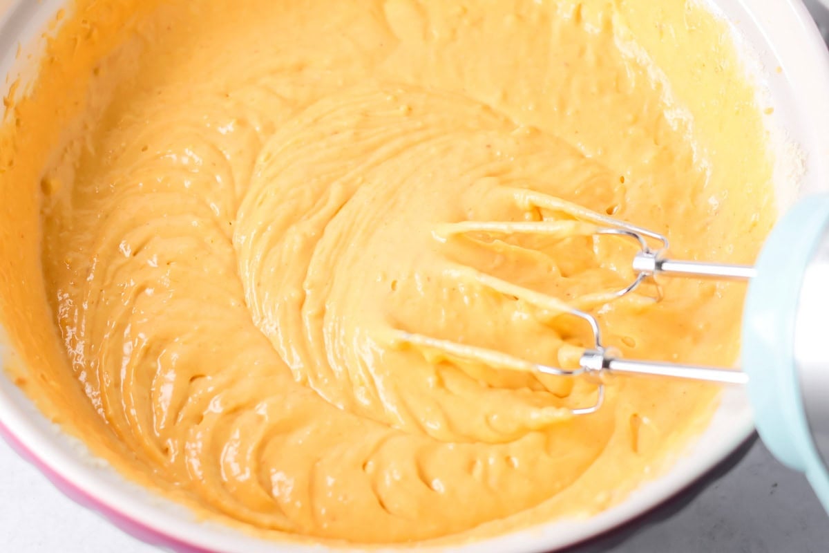Mixing pumpkin honey bun batter in a white bowl.