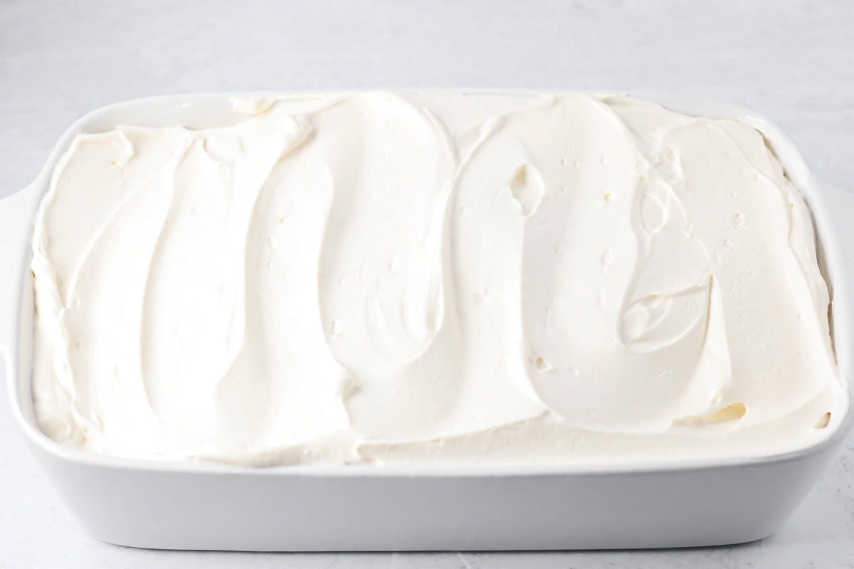 Spreading topping on a baked pumpkin tres leches cake.
