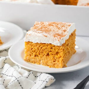 Pumpkin tres leches cake sliced and served on a white plate.