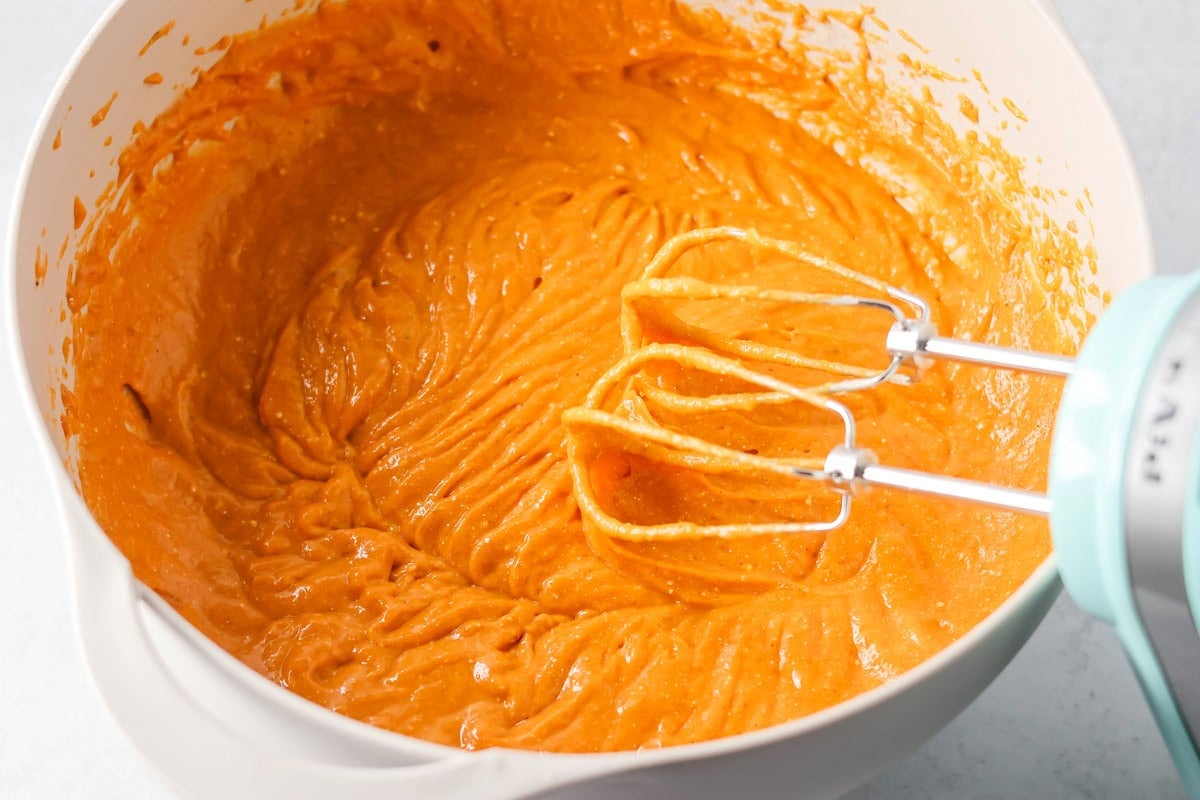 Mixing pumpkin tres leches mixture in a bowl.