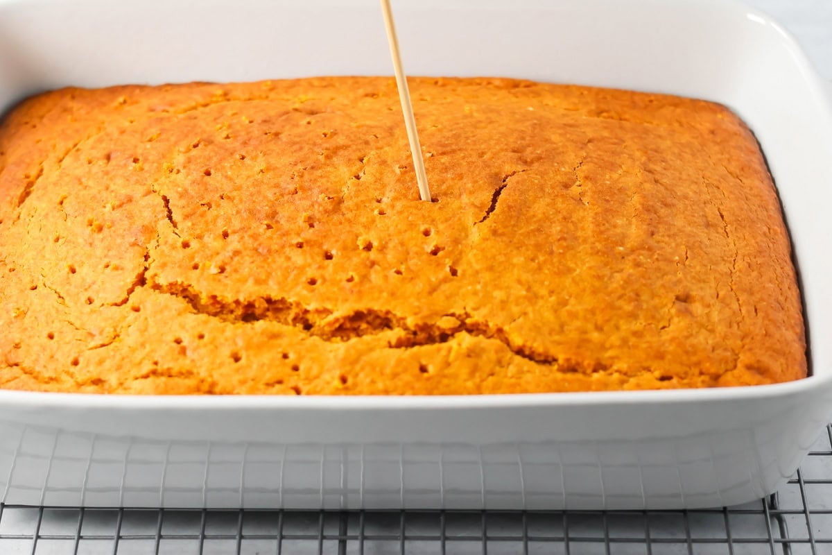 Poking holes in a pumpkin tres leches cake ready for filling.