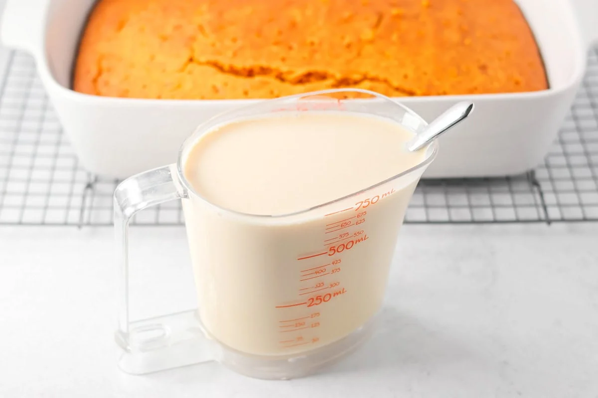 A baked pumpkin tres leches cake with a picture of milk mixture.