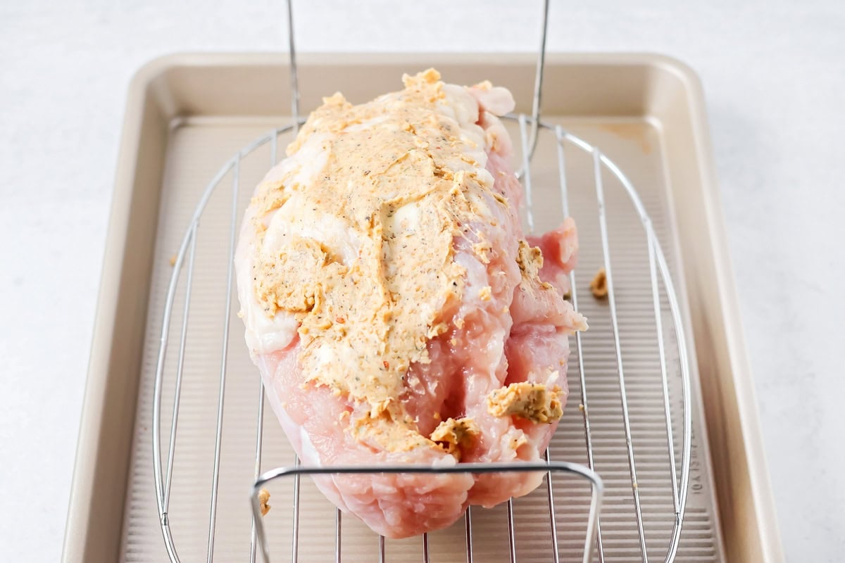 Adding seasoning to a roast turkey breast in preparation for cooking.