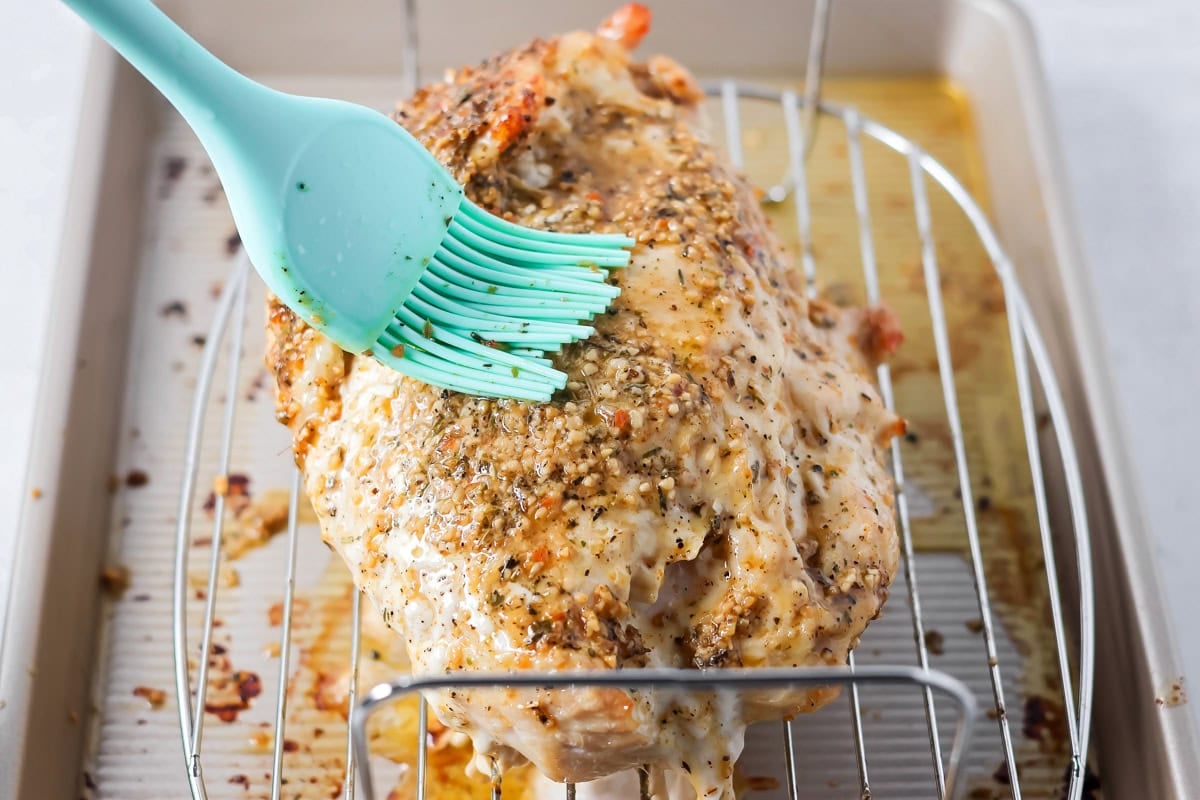 Brushing seasoning on a roast turkey breast.