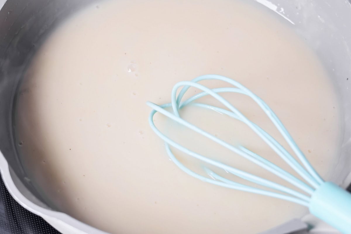 Whisking gravy in a pan for roast turkey breast.